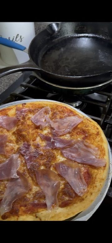 Freshly made pizza topped with sliced cured meat